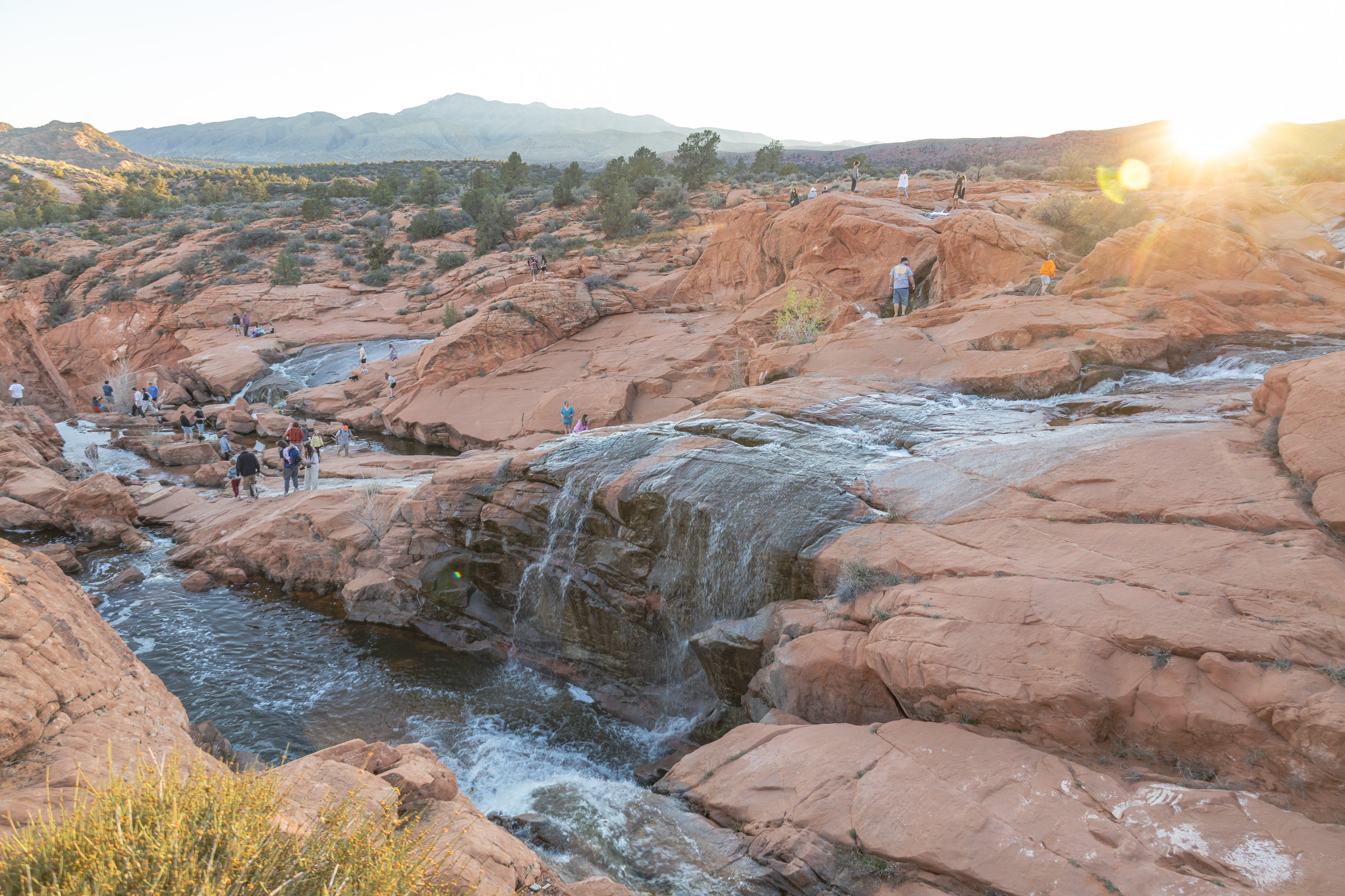 Gunlock Falls near St George Utah flowing during spring runoff with visitors exploring red rock waterfalls